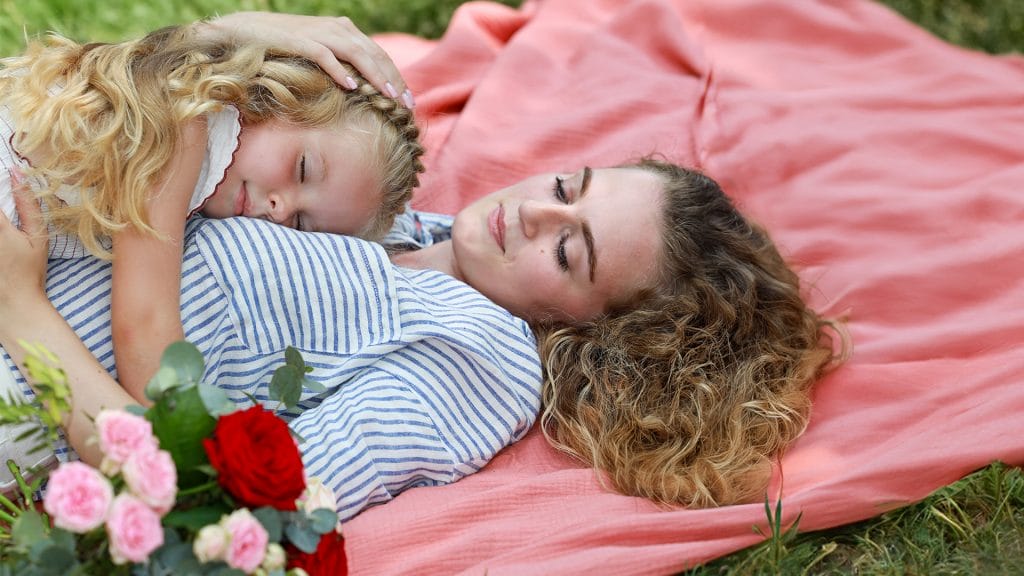 fille allongé sur sa mère avec bouquet de fleur