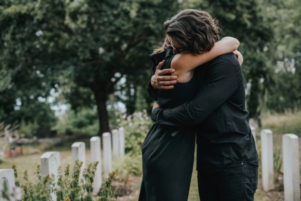 Amis se serrant dans les bras à un enterrement