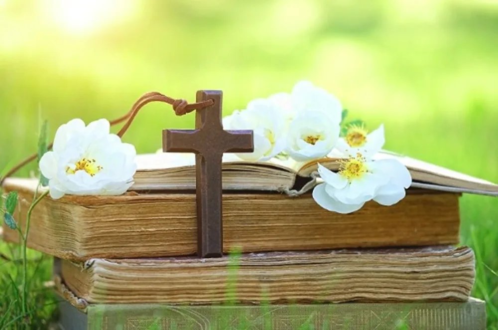 Croix sur un livre avec des fleurs pour la Pentecôte