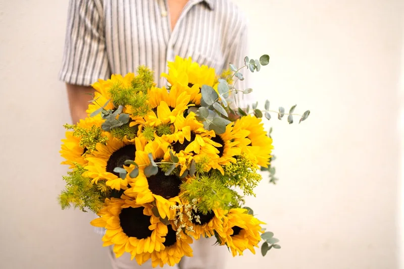 Bouquet de tournesols tenu par un homme