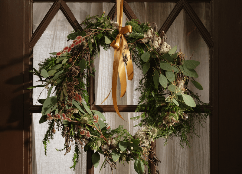 Couronne de Noël composée de cryptoméria, mousse blanche, eucalyptus, saule tortueux, chardons et mélèze.
