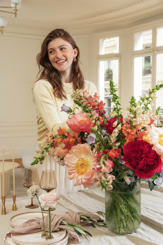 Femme à côté d'un beau bouquet de pivoines dans un vase