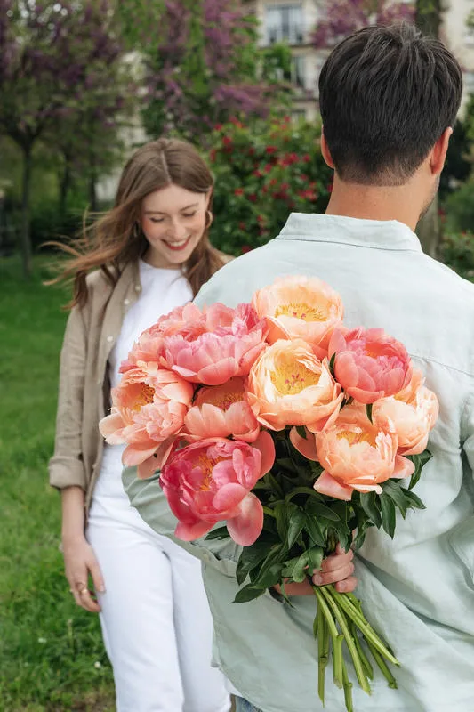 Homme qui offre un beau bouquet de pivoines à sa chérie
