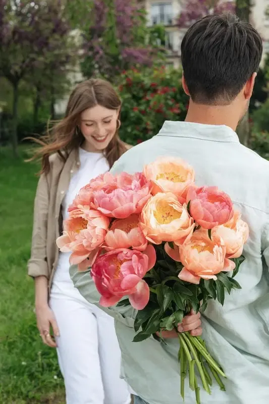 Homme qui offre un beau bouquet de pivoines à sa chérie