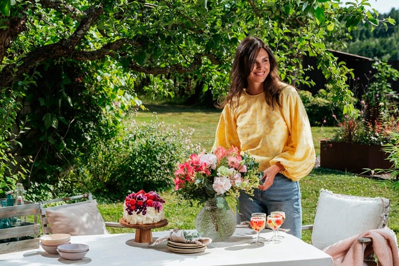 Une femme devant une table d'été dans un jardin