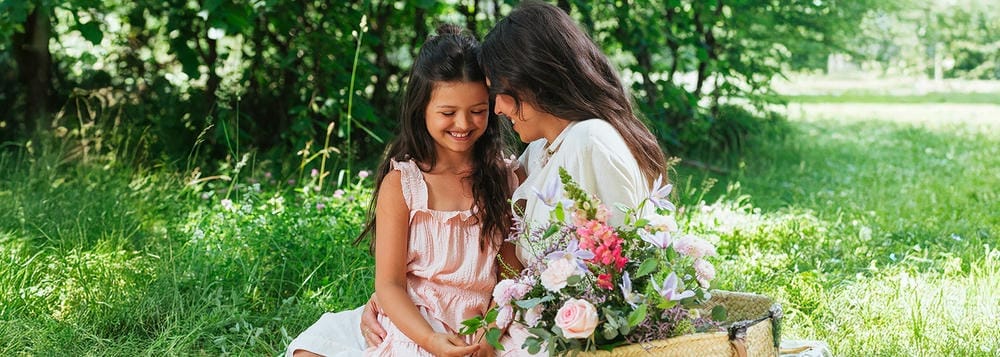Une mère et sa fille souriantes, assises dans l'herbe