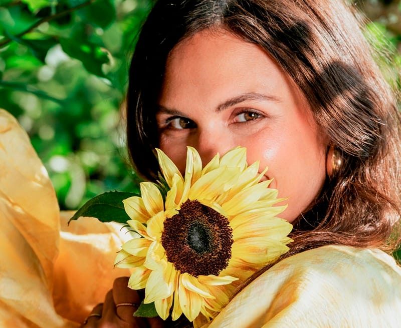 Femme souriante, avec un tournesol devant son visage