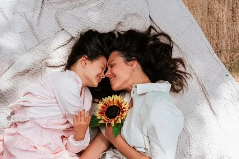 Une mère et sa fille allongées au sol tenant un tournesol