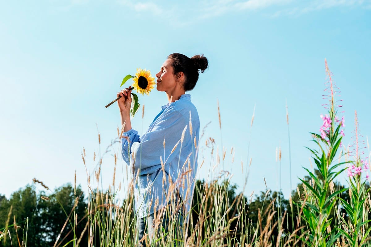 Femme apaisée, respirant un tournesol les yeux fermés