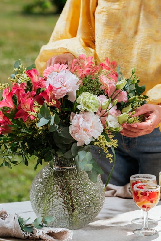 Bouquet de fleurs dans un vase à côté d'apéritifs