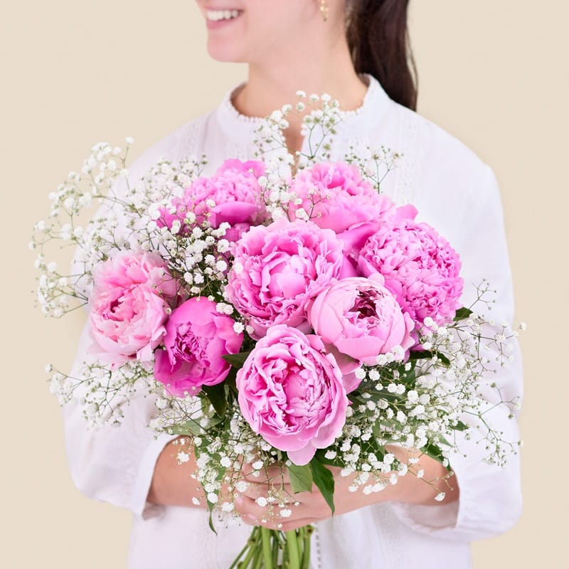 Femme tenant un bouquet de pivoines roses