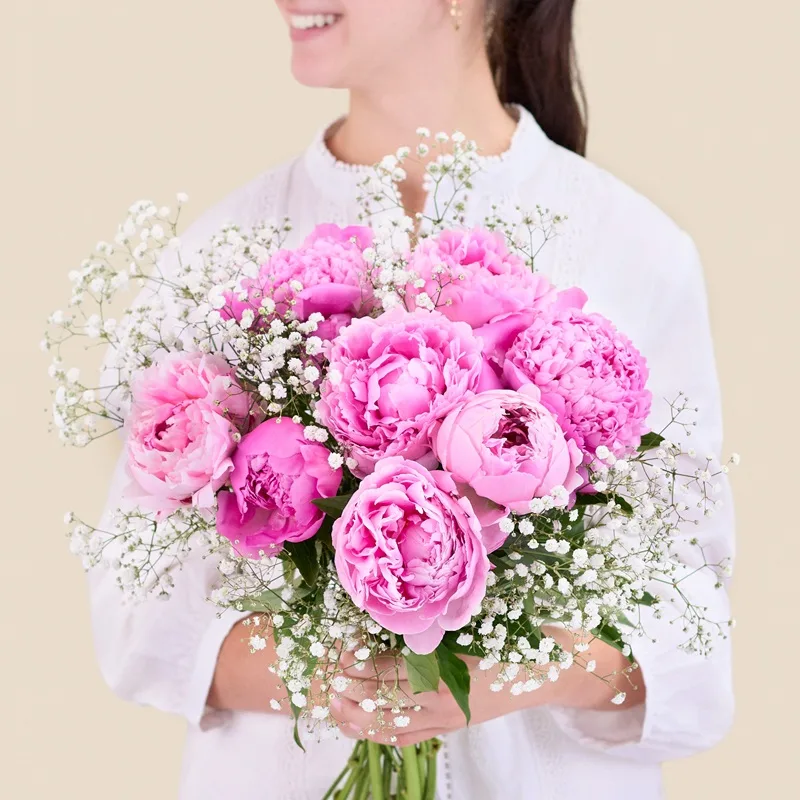 Femme tenant un bouquet de pivoines roses