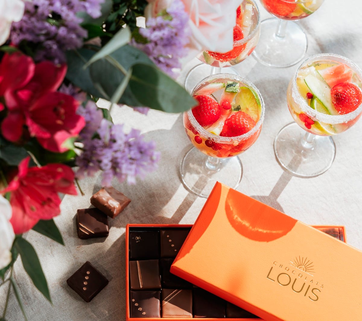 Fleurs, apéritifs et boîte de chocolats disposés sur une table