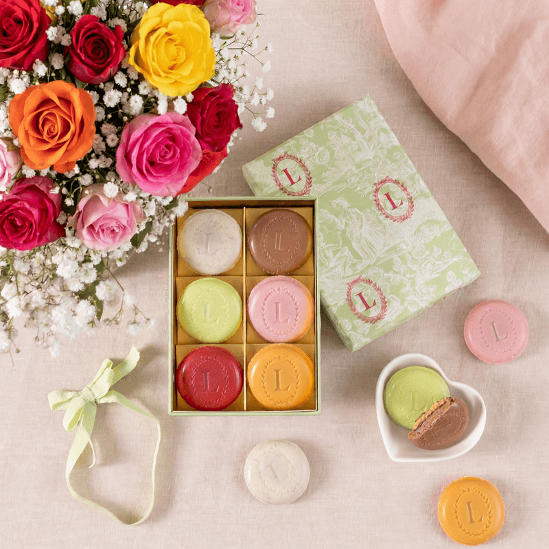 Boîte de macarons Ladurée ouverte et un bouquet de fleurs