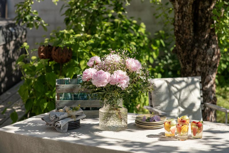 Table d'extérieur décorée d'un bouquet de pivoines et de vaisselle