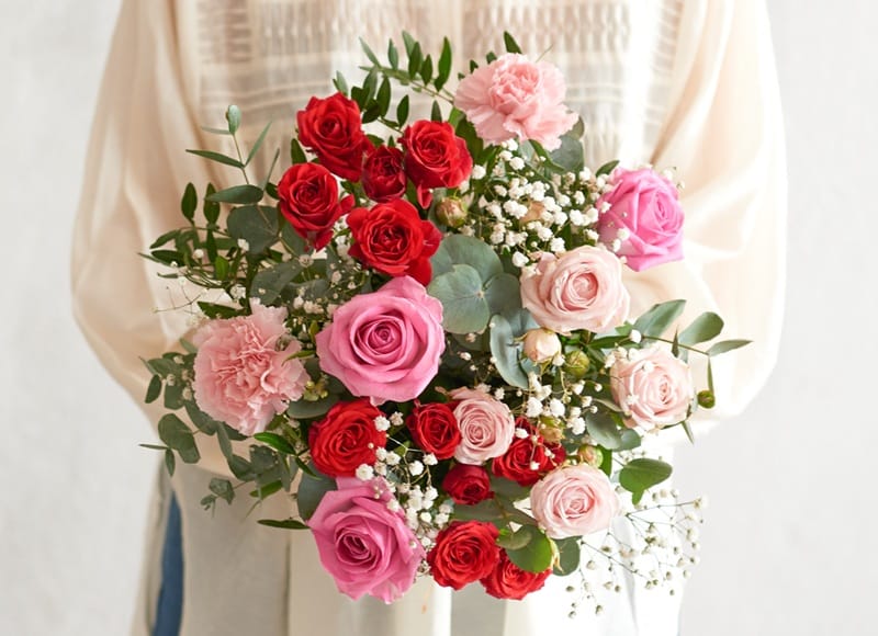 Femme tenant un bouquet de roses coloré