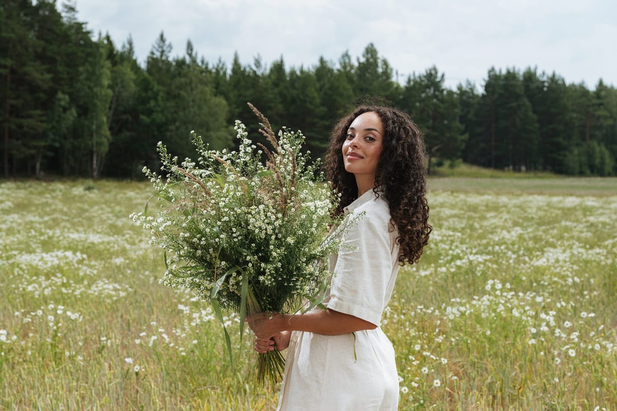 Femme tenant un bouquet de fleurs dans un champ
