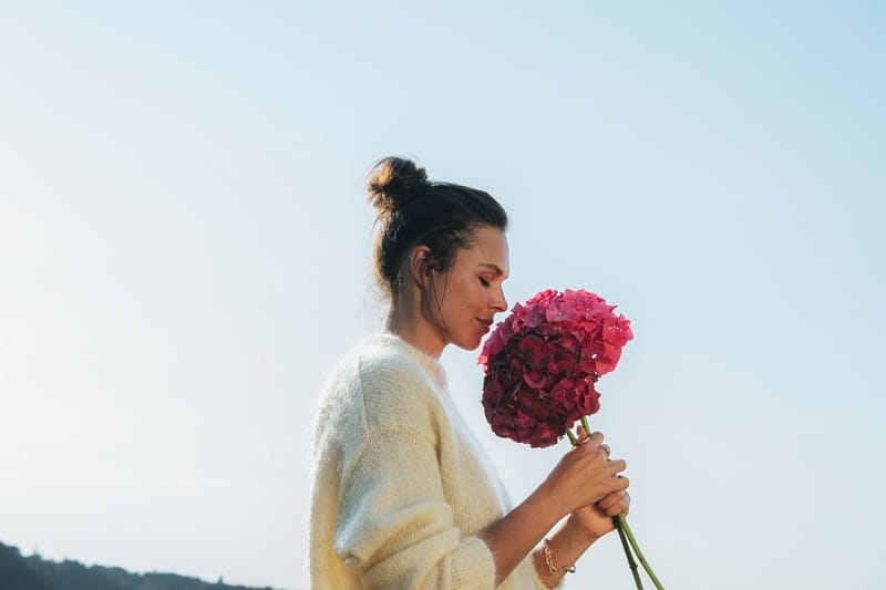 Femme respirant un bouquet d'hortensias
