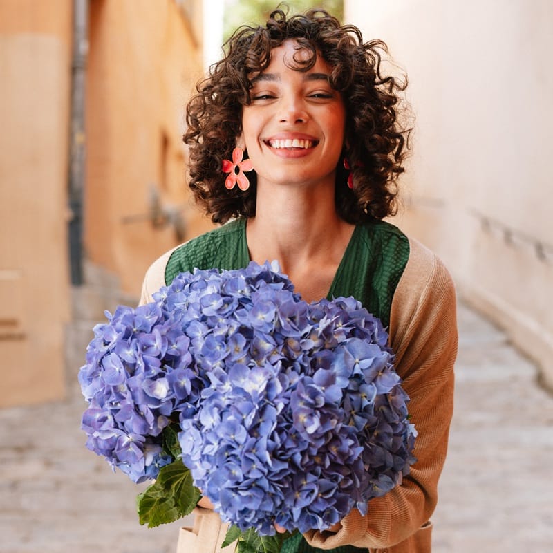 Bouquet d'hortensias bleus tenu par une femme souriante