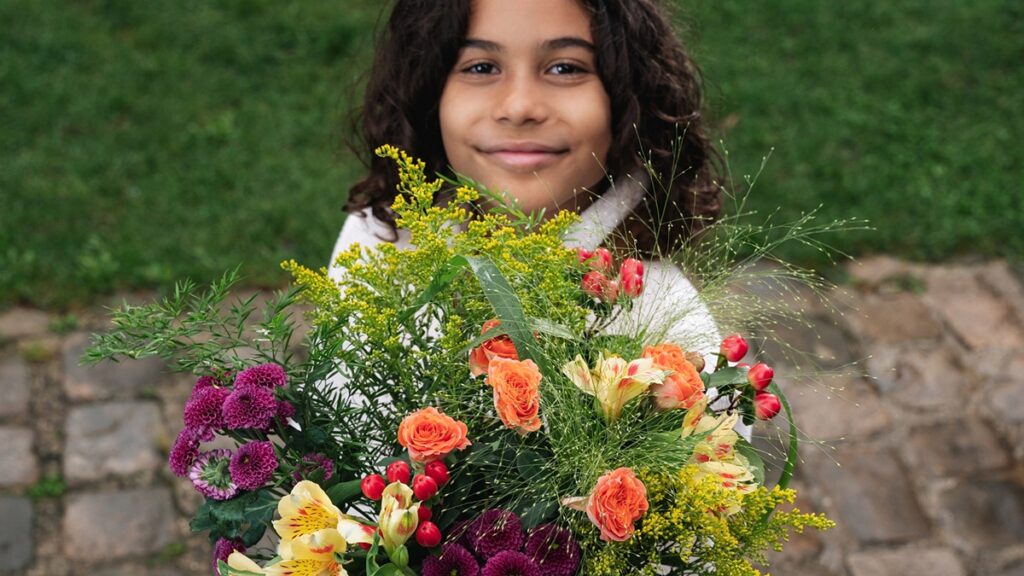 Petite fille tendant un bouquet de fleurs