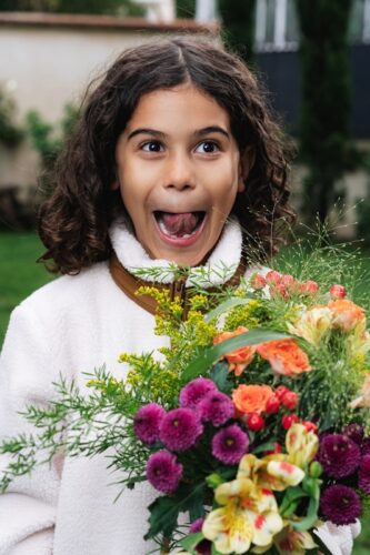 Une petite fille espiègle tenant un bouquet de fleurs