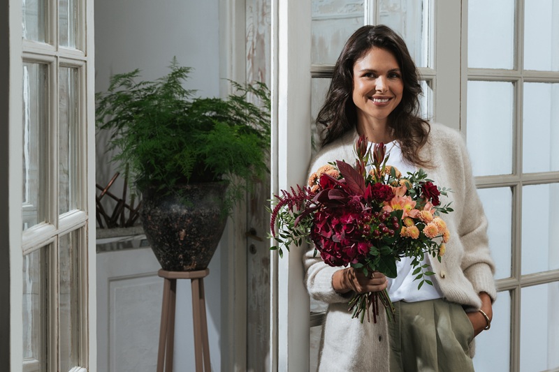 Femme tenant une composition de fleurs aux couleurs d'automne