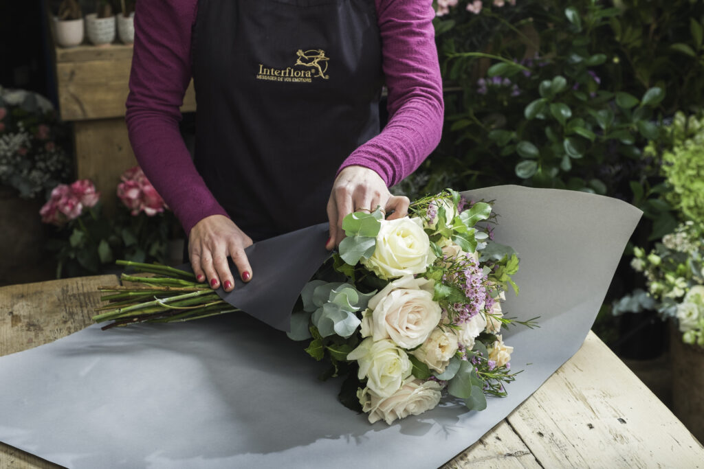 Une fleuriste Interflora emballant un bouquet de fleurs