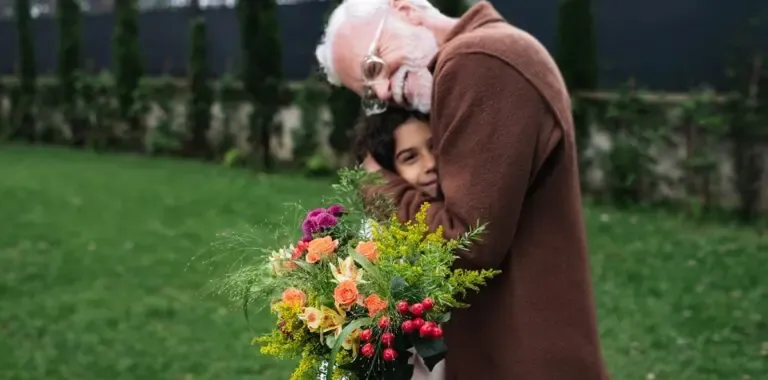 Petite-fille tenant un bouquet et faisant un câlin à son grand-père