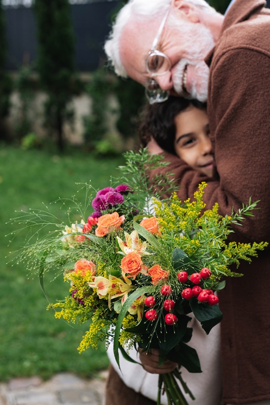 Un grand-père serrant sa petite-fille dans les bras en tenant un bouquet