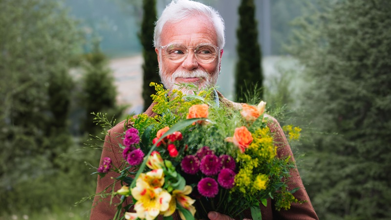 Un grand-père souriant tenant un bouquet de fleurs
