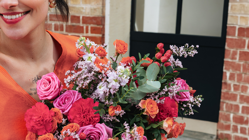 Femme tenant un bouquet de fleurs qui vient de lui être livré