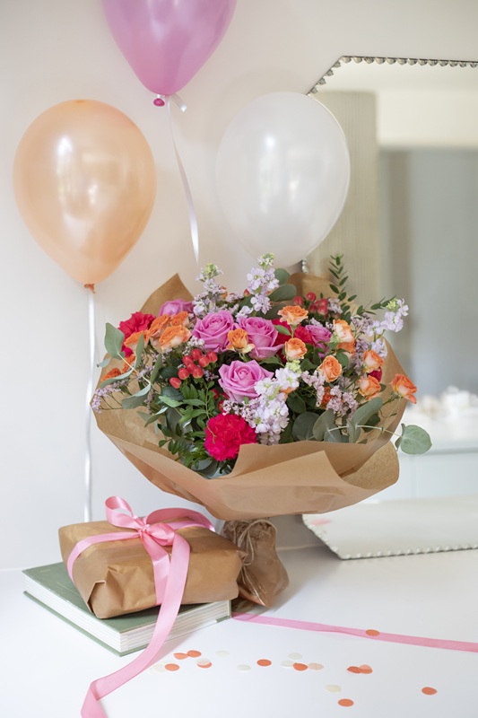 Bouquet de fleurs d'anniversaire à côté d'un cadeau et de ballons