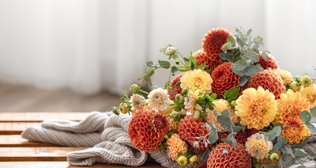 Des fleurs d'automne coupées et un gilet posés sur une table