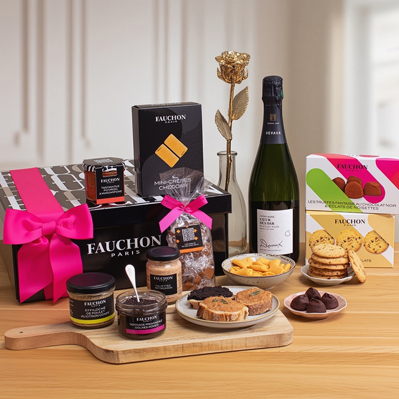 Présentation des produits d'un coffret cadeau Fauchon (bouteille, gâteaux, truffes, tartinades...) accompagné d'une rose en or