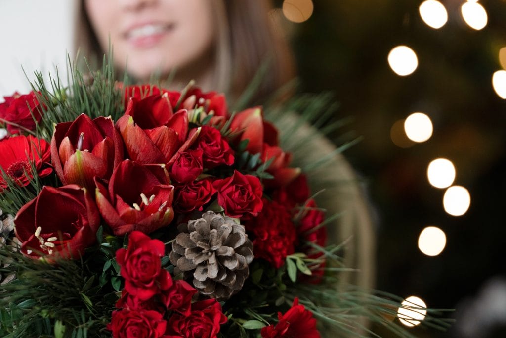 Femme qui sourit tenant un bouquet de Noël rouge
