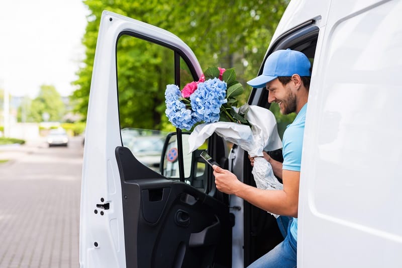 Livreur de fleurs sortant de sa camionnette de livraison