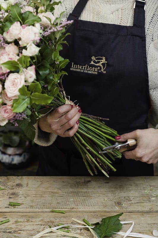 Une fleuriste coupant les tiges d'un bouquet de fleurs