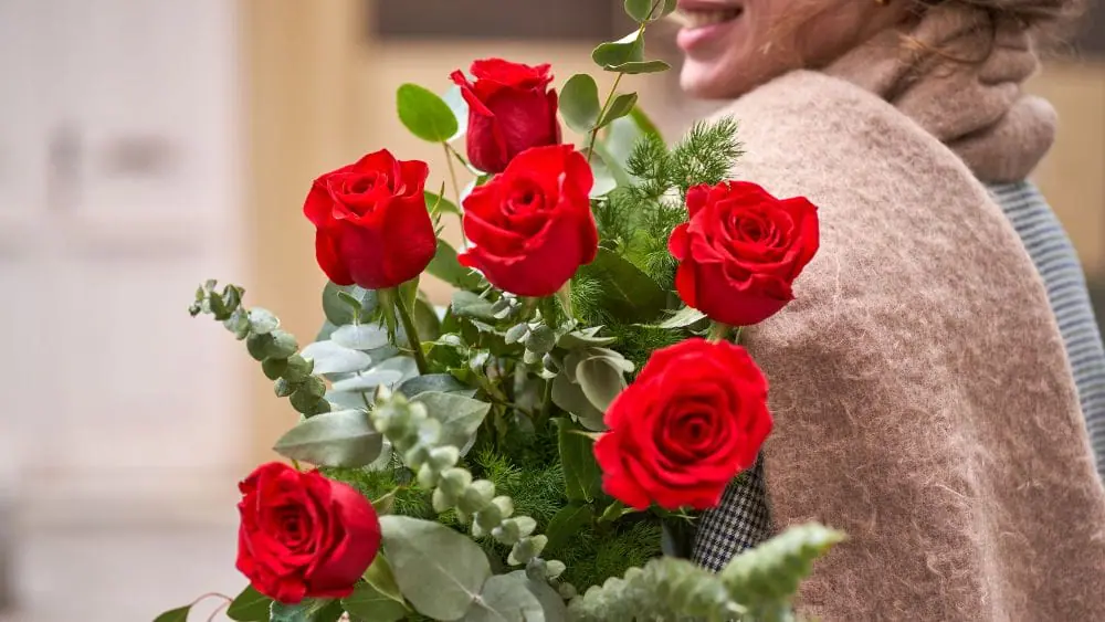 Femme avec un bouquet des roses rouges 
