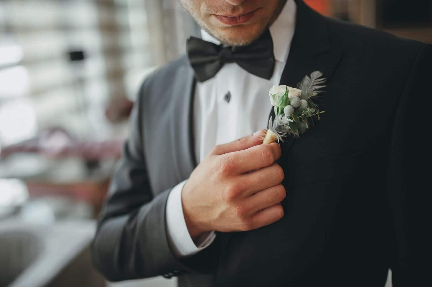 Un homme tenant sa boutonnière de mariage fleurie sur son costume