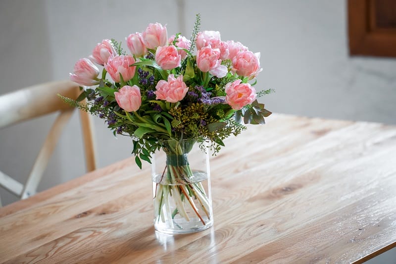 Un bouquet de tulipes roses dans un vase sur une table en bois