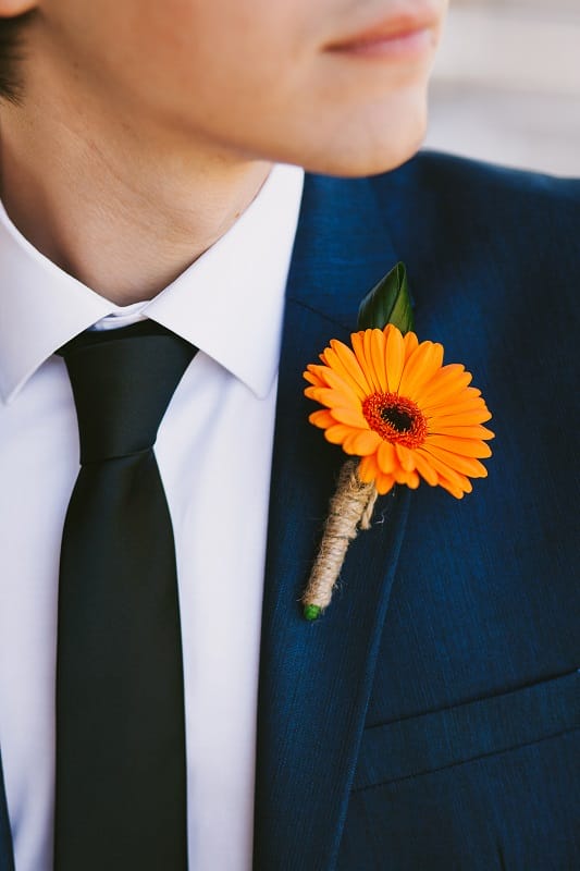 Une boutonnière en fleurs orange entourée d'une ficelle