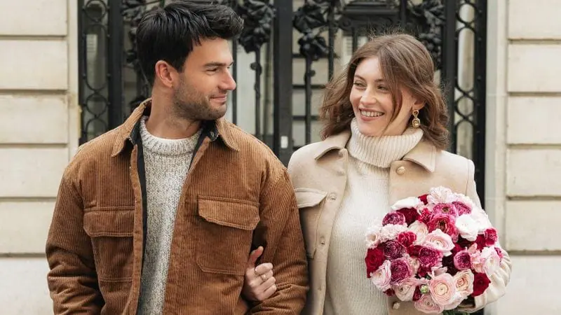 Couple souriants qui se regardent avec un bouquet des fleurs mixtes 