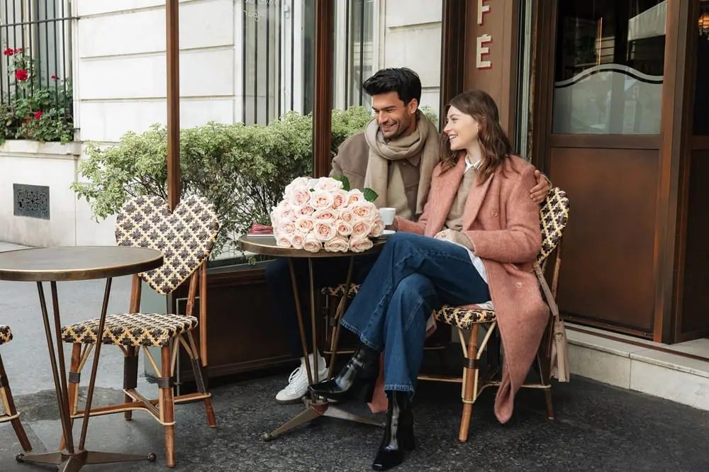 Couple assis en terrasse avec bouquet fleurs roses