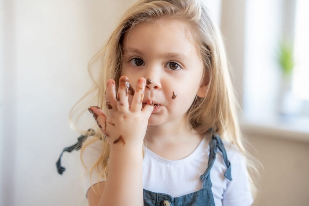 petite fille qui mange du chocolat sur ses doigts