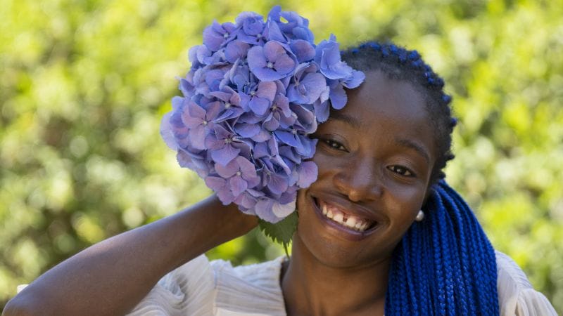 Femme africaine avec bouquet des fleurs violets 