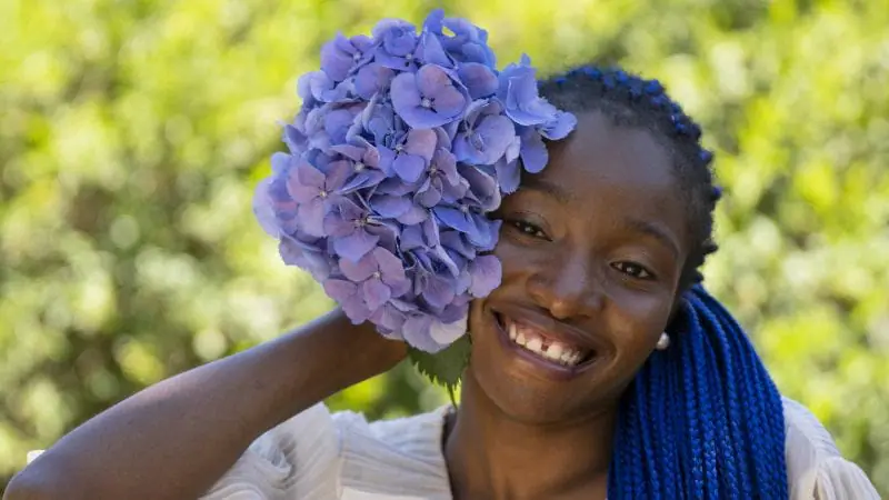 Femme africaine avec bouquet des fleurs violets 