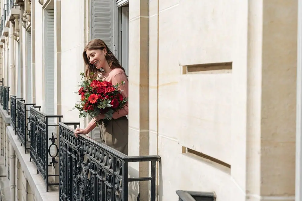 Femme à son balcon avec un bouquet de fleurs rouges