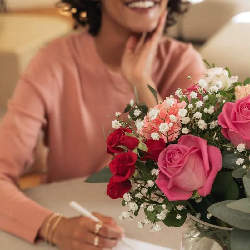 Femme écrivant sur un papier avec un bouquet de fleurs mixtes