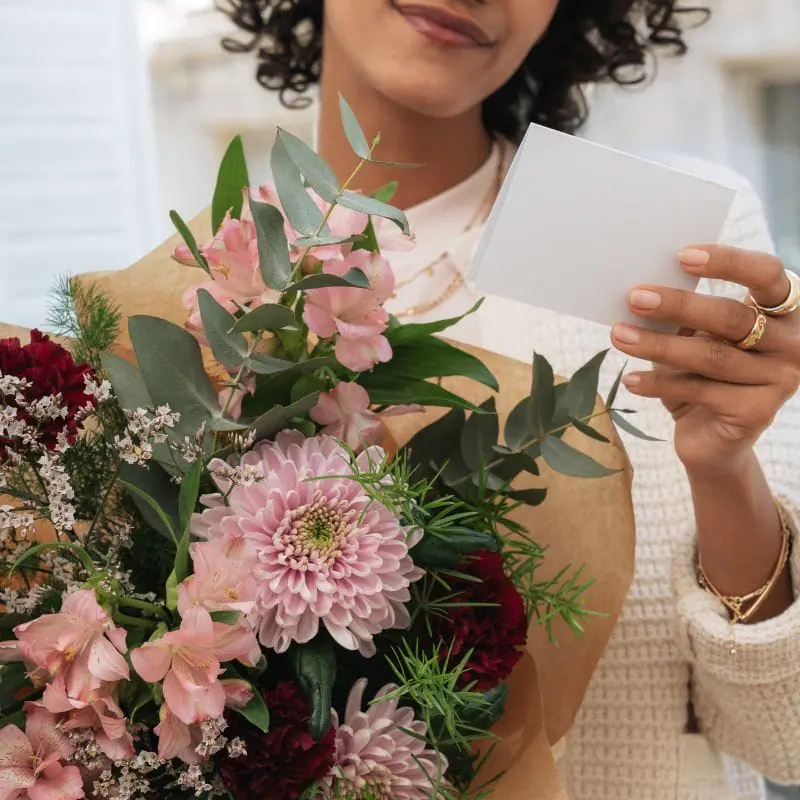 Femme lissant une lettre avec un bouquet des fleurs dans une main 