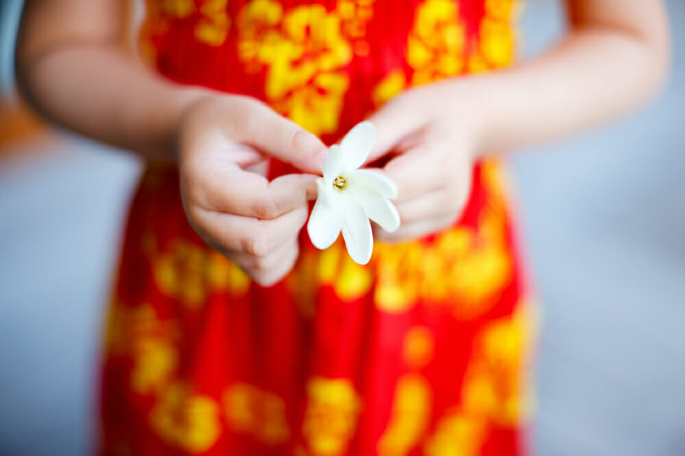 Jeune fille tenant une fleur de Tiaré dans ses mains